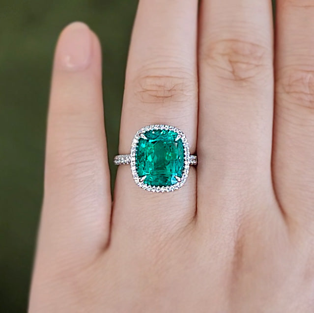 Elongated Cushion Cut Colombian Emerald on a Halo Pave Engagement Ring on wedding finger