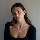 Woman wearing green emerald necklace with bezel and other jewelry.