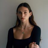 Woman wearing green emerald necklace with bezel and other jewelry.