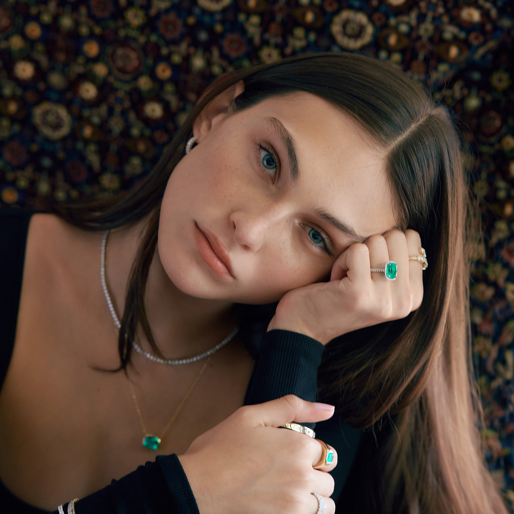 Woman wearing green emerald and diamond jewelry.