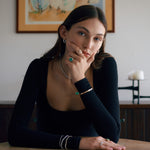 Woman wearing gold and emerald jewelry including rings, bracelets, and necklace.