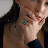 Closeup of green emerald halo ring on woman.