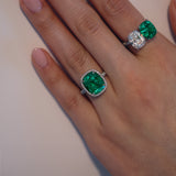 Closeup of woman's hand wearing green emerald and diamond rings.