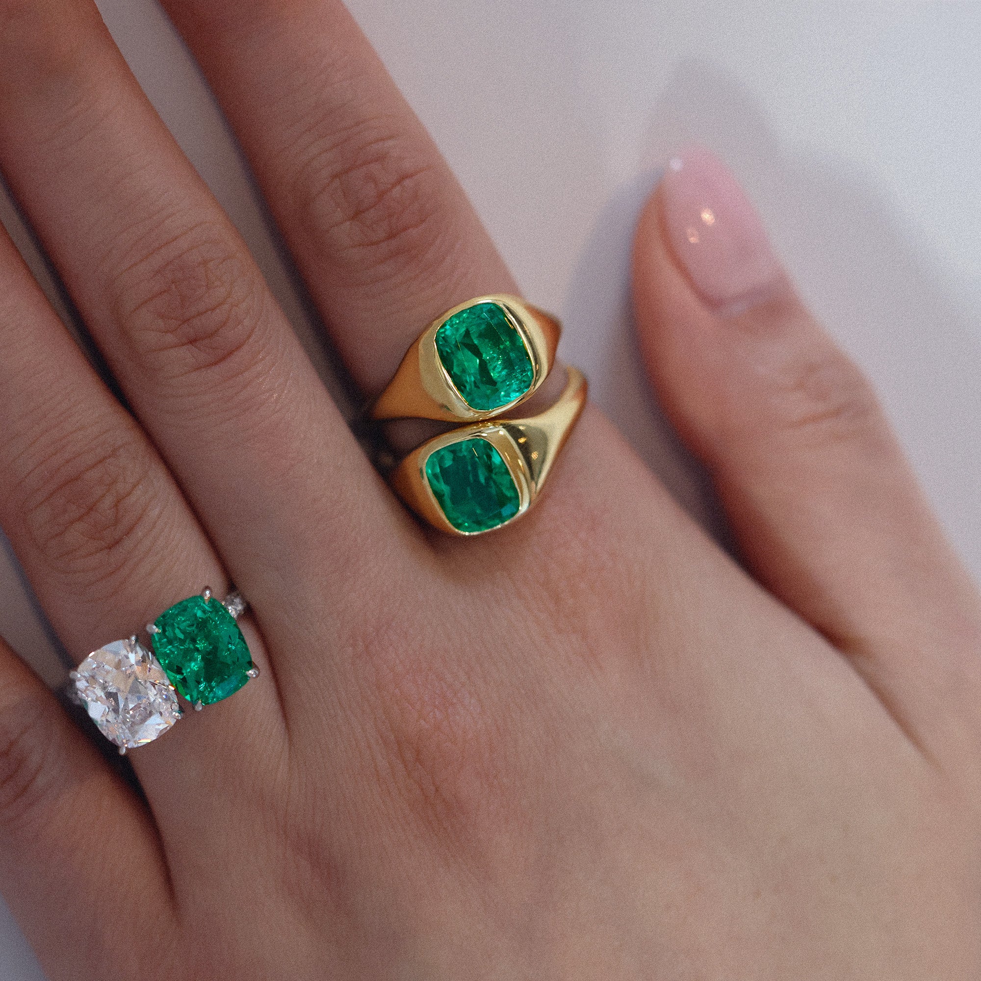 Closeup of green emerald gold rings on woman's hand.