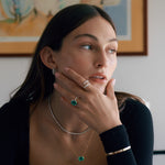 Closeup of woman wearing diamond and green emerald jewelry.