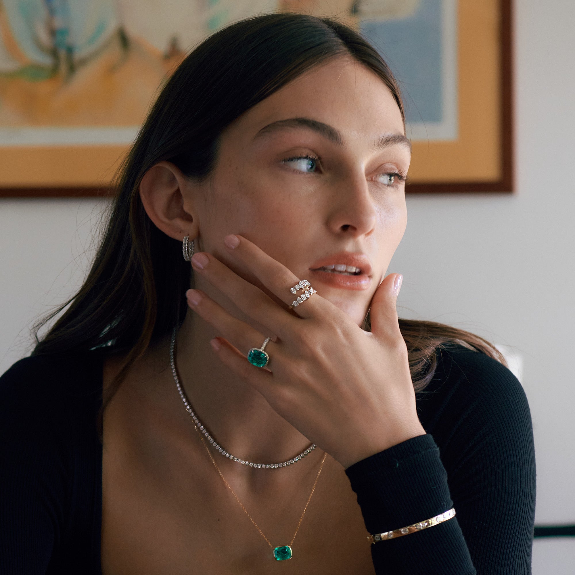 Closeup of woman wearing diamond and green emerald jewelry.